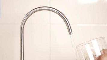 Person fills glass with water form tall arched kitchen faucet video