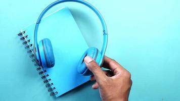 fones de ouvido azuis colocados em um planejador de caderno espiral azul em um fundo azul video