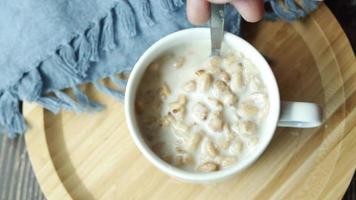 Overhead view of mixing milk in a bowl of chunk granola cereal in a ceramic mug video