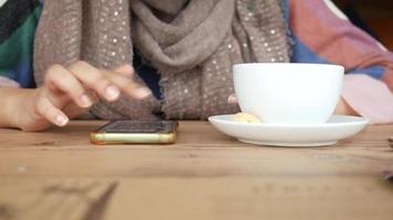 Woman having coffee and uses smartphone video
