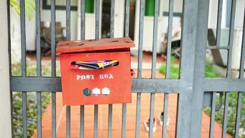 buzón rojo al aire libre lleno de correo adjunto a la valla de hierro