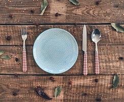 Time for dinner High angle shot of empty plate, fork, spoon, knife lying on rustic table photo