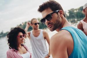 salir con amigos. grupo de jóvenes con ropa informal sonriendo y divirtiéndose mientras están en el muelle foto