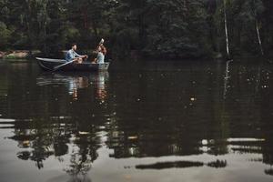 Little adventure. Beautiful young couple enjoying romantic date and smiling while rowing a boat photo