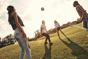 grupo de jóvenes sonrientes con ropa informal jugando al fútbol mientras están de pie al aire libre foto