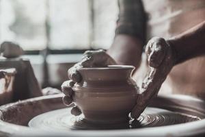 Potter at work. Close-up of man making ceramic pot on the pottery wheel photo