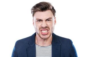 Furious man. Portrait of furious young man grimacing and looking at camera while standing against white background photo
