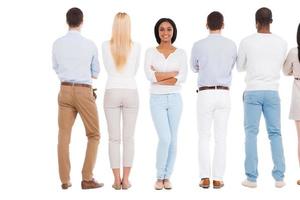 Now it is my turn. Rear view of group of people standing in a row and against white background while one beautiful African woman standing face to camera and smiling photo