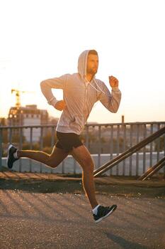 Keep on moving Side view of confident young man looking forward while running along the bridge photo