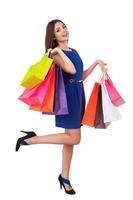 Shopaholic girl. Full length of beautiful young woman in blue dress holding shopping bags and smiling at camera photo