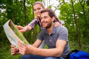 turistas examinando el mapa. pareja joven pensativa con mochilas examinando el mapa mientras está de pie en la naturaleza foto