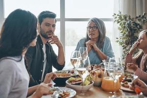 Happy multi-generation family communicating and smiling while having dinner together photo