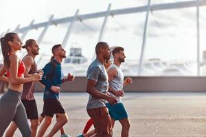 Group of young people in sports clothing jogging together outdoors photo