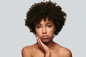 Bored. Upset young African woman looking at camera and making a face while standing against grey background photo