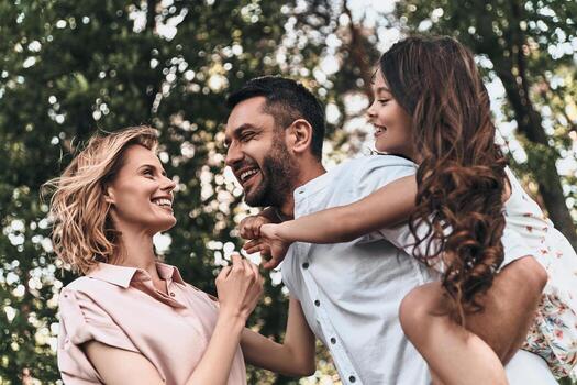 Enjoying every moment together. Happy young family of three smiling while spending free time outdoors photo