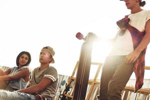 Life filled with friendship. Group of young modern people hanging out together while spending time at the skate park outdoors photo