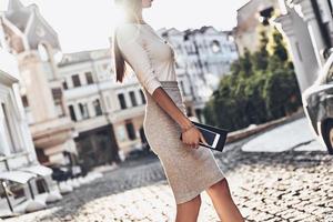 Businesswoman on the go. Close-up of young woman carrying her smart phone and wallet while walking outdoors photo