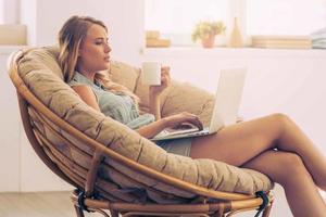 https://static.vecteezy.com/system/resources/thumbnails/013/572/810/small/surfing-web-at-home-beautiful-young-woman-working-on-laptop-and-holding-coffee-cup-while-sitting-in-big-comfortable-chair-at-home-photo.jpg