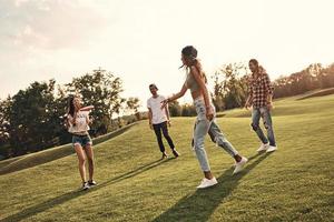 juegos activos. toda la longitud de jóvenes sonrientes con ropa informal jugando frisbee mientras pasan tiempo sin preocupaciones al aire libre foto