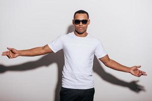 It is all about me Confident young African man in sunglasses stretching out hands and looking at camera while standing against white background photo