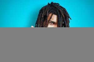 Happy young African man in casual wear smiling and showing call me gesture while standing against blue background photo