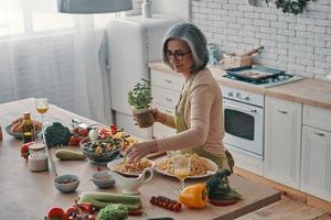 vista superior de una anciana en delantal cocinando una cena saludable mientras pasa tiempo en casa foto