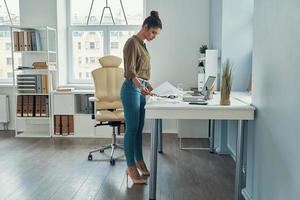 Full length young woman in smart casual working in the office photo