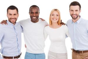 equipo de negocios feliz. cuatro jóvenes felices con ropa informal elegante mirando la cámara mientras se unen entre sí y se enfrentan a fondo blanco foto