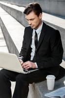 Working Outdoors. Cropped image of Cheerful businessman using laptop photo