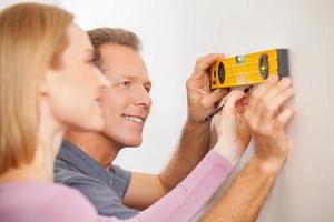 Couple measuring wall. Cheerful mature couple taking measurements of the wall and smiling photo