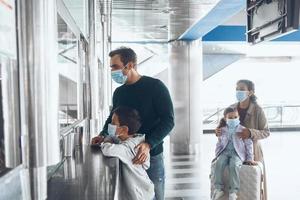 Family with two little kids in protective face masks buying tickets at ticket counter photo