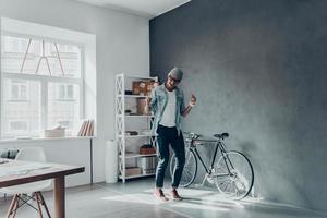 Full length of handsome young man in eyewear gesturing and keeping mouth open while standing in creative office photo