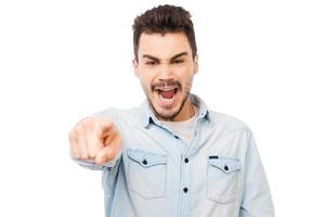 You are wrong Frustrated young man pointing you and shouting while standing against white background photo