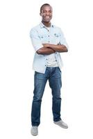 Casually handsome. Full length of handsome young black man keeping arms crossed and smiling at camera while standing against white background photo