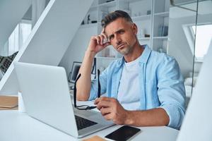 Confident mature man looking at camera while sitting at the office desk photo