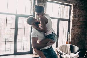 Beautiful couple.  Young passionate couple having fun together and looking happy while handsome young man carrying his girlfriend in hands photo
