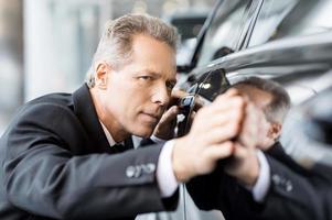 Perfect lines.  Mature grey hair businessman examining car at the dealership photo