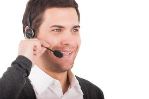 Representante de Servicio al Cliente. hombre joven guapo en auriculares mirando hacia otro lado y sonriendo mientras está de pie aislado en blanco foto