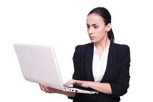 empresaria navegando por la red. bella joven con ropa formal trabajando en una laptop aislada de fondo blanco foto