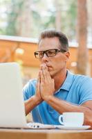 Coffee break. Thoughtful mature man drinking coffee and looking away while sitting in sidewalk cafe photo