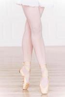 Perfect position. Close-up of ballerina legs in white tutu and slippers photo