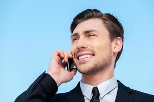 Successful businessman. Cheerful young men in formalwear talking on the mobile phone while standing outdoors photo