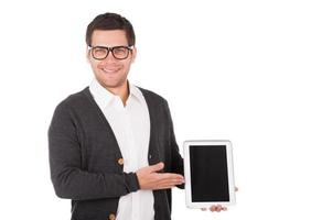 Presenting a brand new digital tablet. Cheerful young man holding a digital tablet and pointing it while standing isolated on white photo