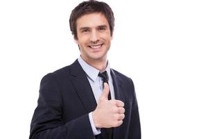 Hombre de negocios exitoso. joven feliz en ropa formal mostrando su pulgar hacia arriba y sonriendo mientras está de pie aislado sobre fondo blanco foto