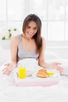 es todo esto para mí una joven sorprendida mirando la bandeja con el desayuno y sonriendo mientras estaba sentada en la cama y cubierta con una manta foto