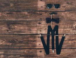 Pure elegance. High angle shot of suspenders, prop, bow tie and eyewear lying on wooden desk photo