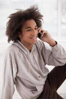 Calling friends. Cheerful African teenager talking on the mobile phone and smiling photo