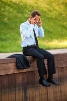 Depressed businessman. Depressed mature businessman holding head in hands while sitting at the quayside photo