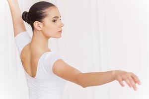 Preparing for pirouette. Beautiful young ballerina in white tutu dancing in ballet studio photo