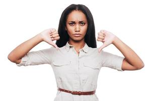 I say no Confident young African woman keeping her thumbs down while standing against white background photo